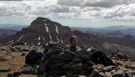 Suzy on Wetterhorn Peak signing the summit register, with Uncompahgre Peak in the background